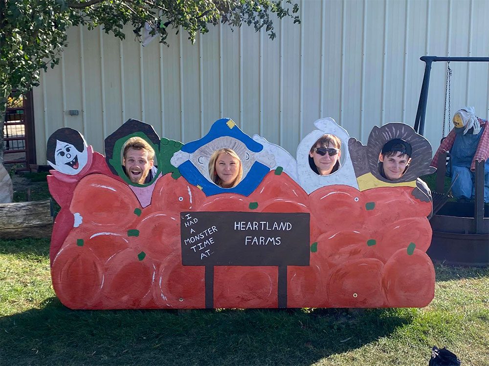 Each month, our corporate team has an outing to bond as a team. In October, we went to Heartland Farms Waterloo and got to be like kids again! Team posing at a photo stand in